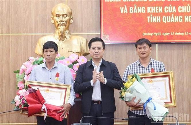 Chairman of the Quang Ngai provincial People's Committee Nguyen Hoang Giang (centre) presents the State President's Bravery Order to two citizens of Ly Son special zone on December 15. (Photo: VNA)